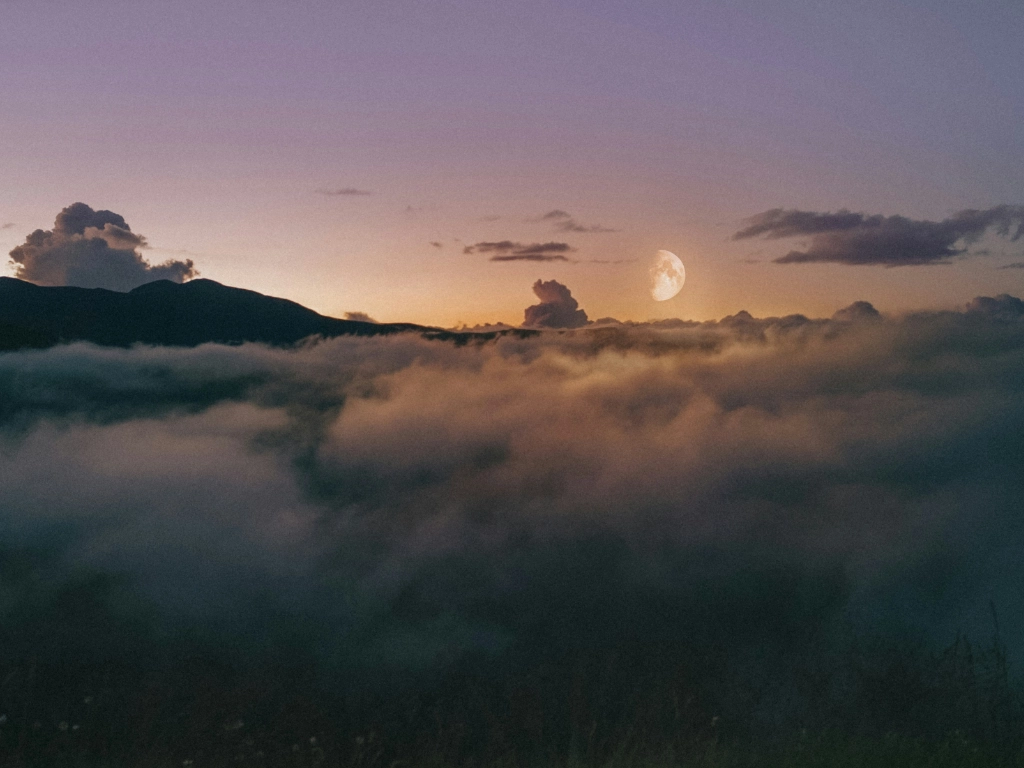Sonnenaufgang und Mond über den Wolken sichtbar